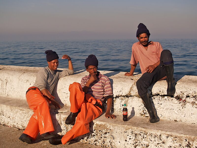 Time to relax three men sitting by the sea with a bottle of coke